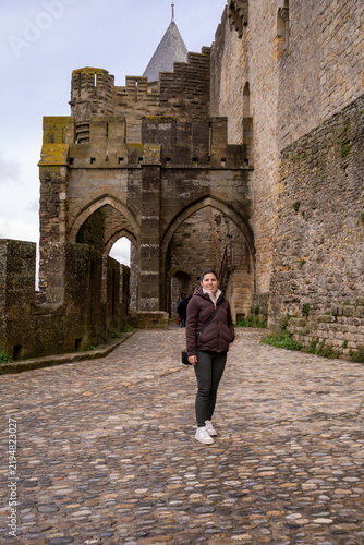 Fotografie Woman Standing in Medieval Castle Court with Stone Ramparts and Conical Tower