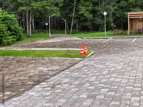 Empty Paved Parking Lot with Safety Cones and Wooden Building