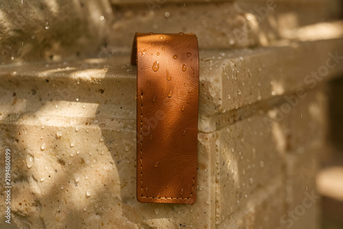 Vegetable-tanned leather door pull resting on a polished stone entryway console