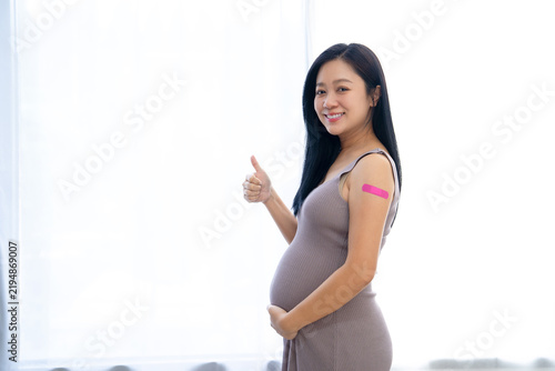 Happy Pregnant Asian Woman received anti virus vaccine cheerful with bandage. Vaccination in Pregnant Concept