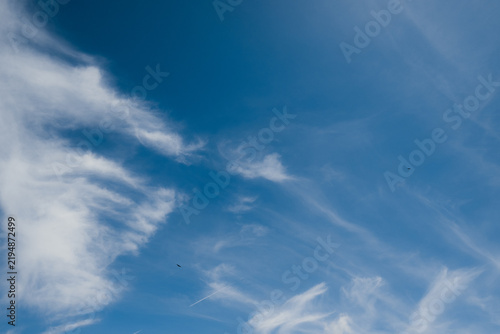 Blue sky with wispy cirrus clouds and contrail
