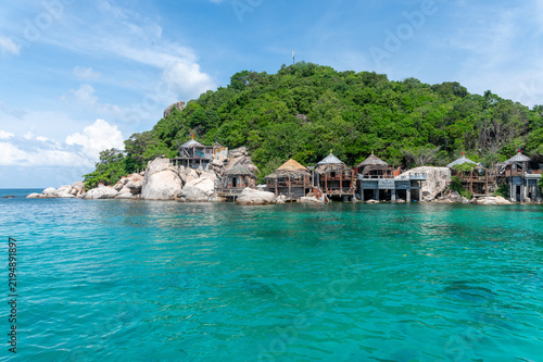 Foto Abandoned bamboo stilt huts along a rocky tropical shoreline in Koh Tao, Thailand, with clear turquoise water and dense green vegetation