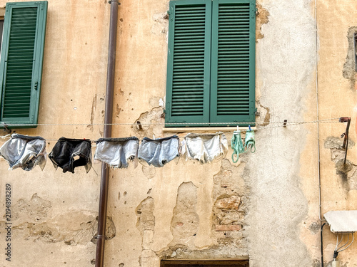 Traditional Italian street scene with clothes drying on a line across a rustic peeling building facade