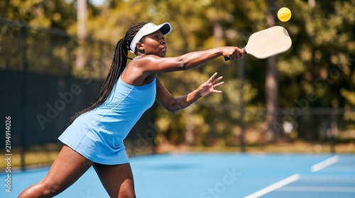 Female pickleball player reaching for high ball on court