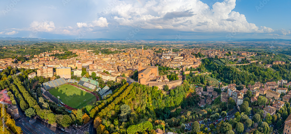 Obraz premium Aerial panoramic view of the Italian famouse city Siena with the landmarks of Basilica di San Domenico, Piazza del Campo tower and Duomo di Siena standing out over the old town center