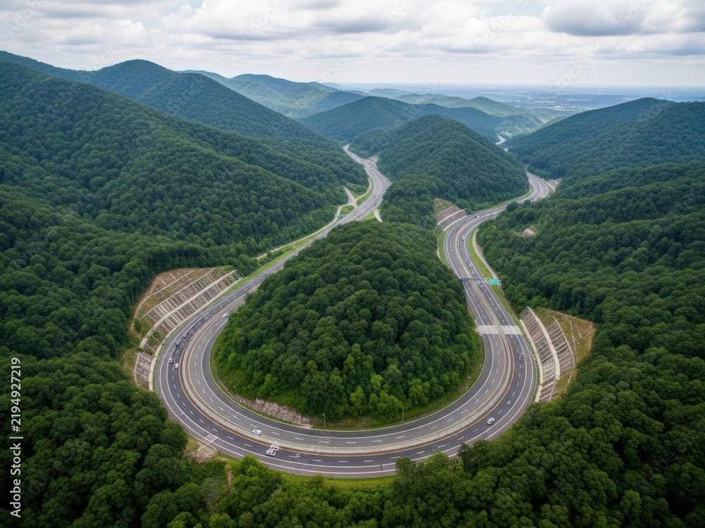 Obraz premium Spiral mountain road winding through green forest landscape