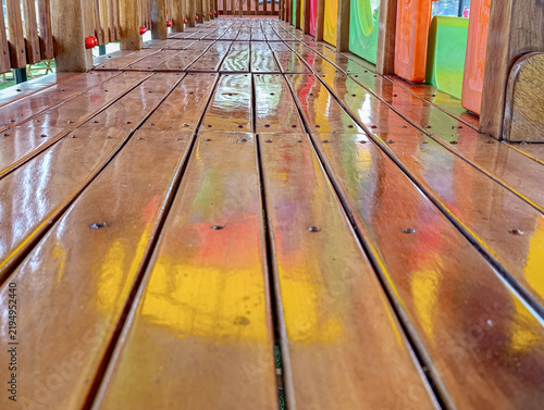 Close-up of polished wooden floor planks on a colorful outdoor children's playground structure with glossy varnish reflection.