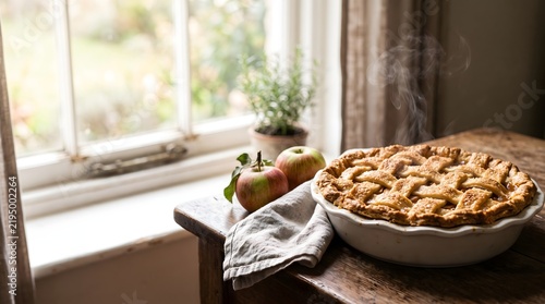 A delicious homemade apple pie sitting on a rustic wooden table near a bright window for a cozy thanksgiving celebration