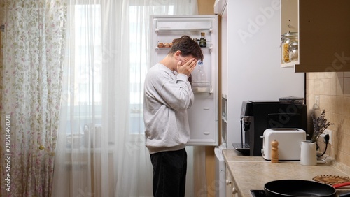 Obraz na plátně Young man covering his face with hands, feeling stressed and desperate while loo