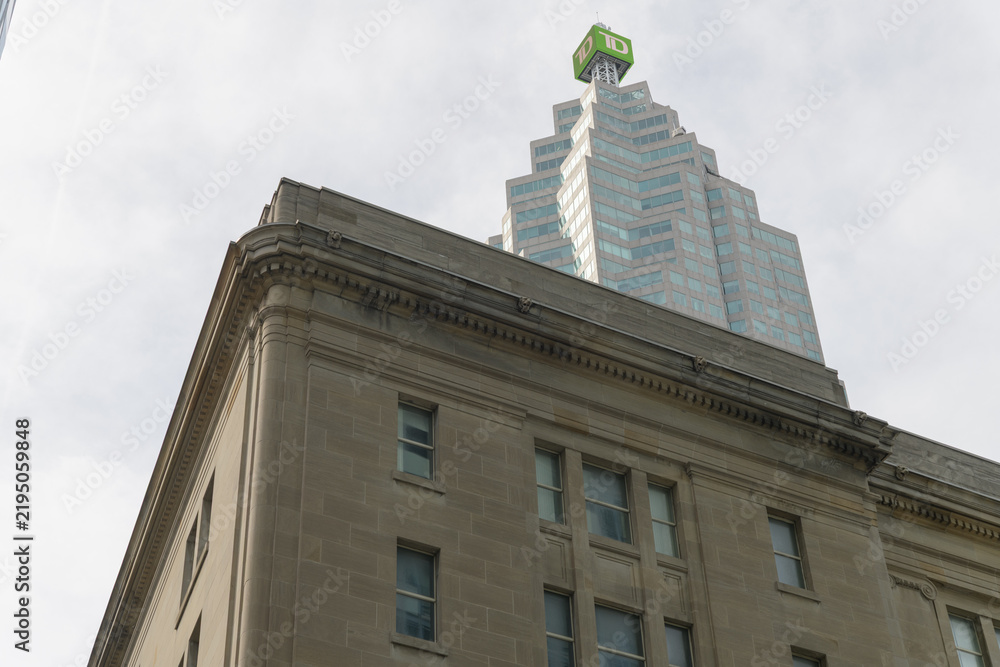 Obraz premium contrast of old building with modern office building: southeast corner of Dominion Public Building (1 Front St W) and TD Place with corporate logo shield at 161 Bay St, Toronto