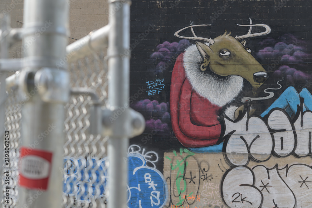 Fototapeta premium defocused view of a barrier fence and detail of street art mural by Greg Mike and Big Teeff located at 464-470 Queen St W, Toronto