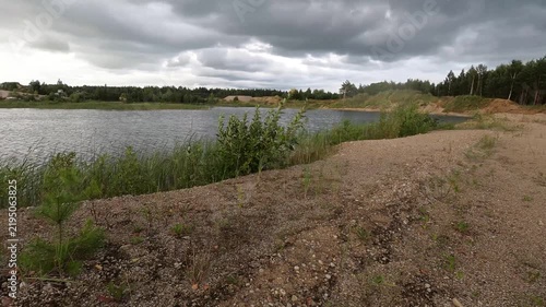 Panning View of Gravel Lakeshore and Water Under Dark Clouds