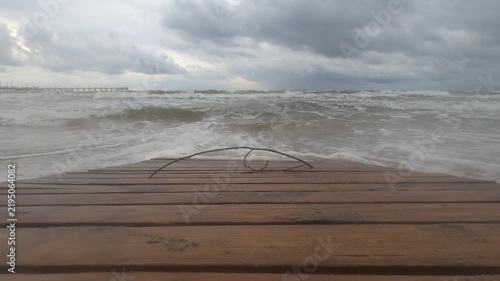 Rough sea waves approaching a wooden shoreline deck