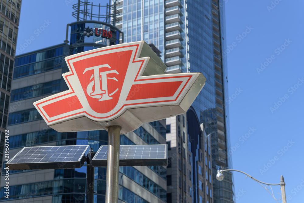 Obraz premium subway entrance sign or TTC shield logo sign outside a station on University Av, Toronto (defocused sign of UBS Bank & Wealth Management)