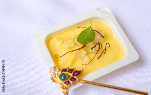 Close up of white bowl of 'Makhan misri' or butter candy with golden flute to laddu Gopal, a Hindu god lord Krishna during the Janmashtami festival.
