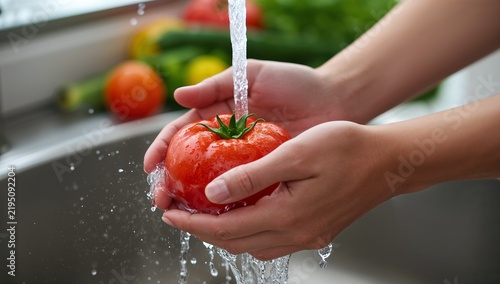 Close up of hands people washing vegetables by tap water at the sink in the kitchen to clean ingredient prepare a fresh salad.
