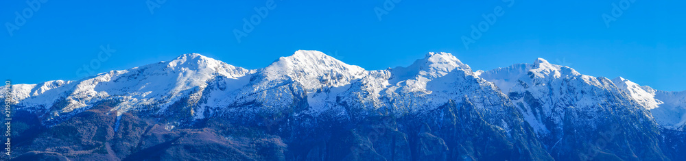 Obraz premium Panoramic view of the snow-capped peaks of the Monte Baldo range on Lake Garda. The third peak from the left is the highest peak, Cima Valdritta (2,218 m).