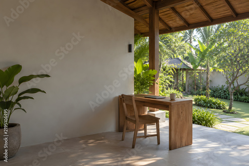 Shaded tropical terrace workspace with wooden desk and garden view
