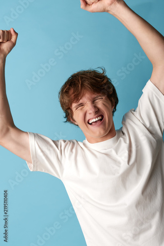 Quadro su tela A man in a white shirt raises arms in a tilted pose, smiling with closed eyes