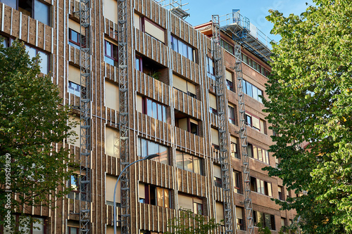angled view of renovated building facade with wood-effect insulation cladding and trees