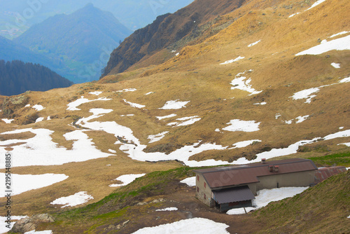 Фотография Lonely rustic alpine hut Baita Foppabona in a foggy mountain meadow with first w