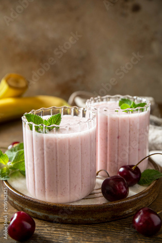 Pink cherries and banana fruit smoothie or milk protein shake on stone tabletop. Yogurt cocktail, natural detox. Liquid ice cream. Copy space.