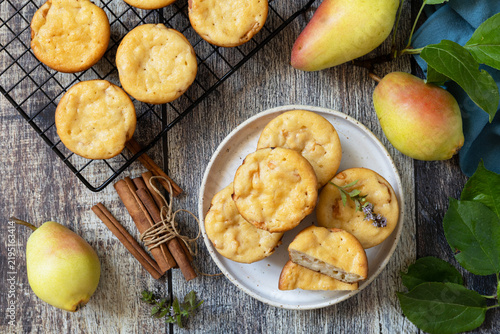 Homemade biscuit cakes sweet cottage cheese muffins with pear, cinnamon on a rustic wooden tabletop. Autumn vegetarian baking. View from above.