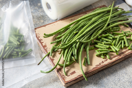 Vacuum sealed fresh green beans in packaging on a light grey background, healthy eating, zero waste, meal prep concept.