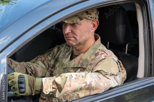 Cuadro en lienzo Serious soldier in camouflage uniform sitting inside a car