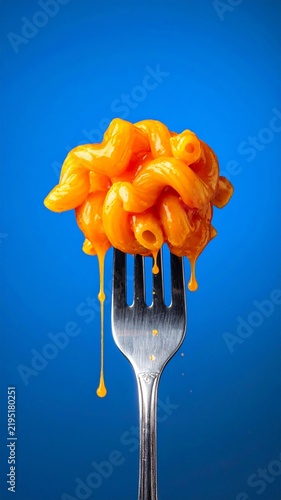 Macaroni and Cheese on Fork with Melting Cheddar Sauce on Blue Background