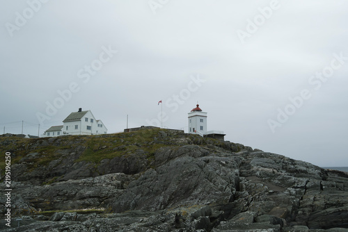 Lighthouse on rocky coastline under mist