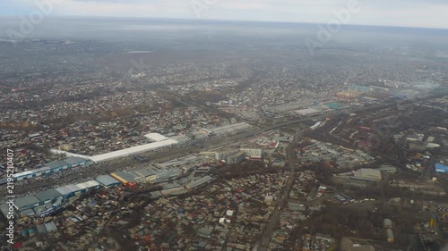 Aerial view flying high over suburban city landscape with buildings and roads under overcast sky, wide shot