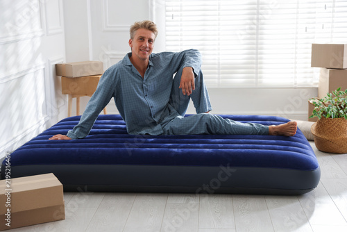 Happy man in pajamas on air mattress at home