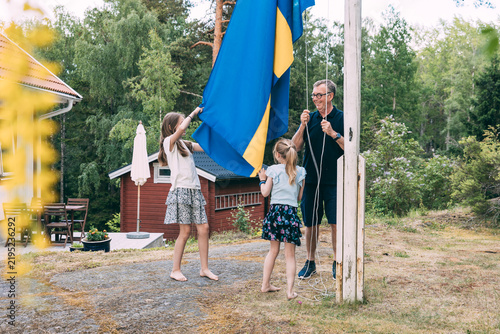 Man raising Swedish flag with his granddaughters
