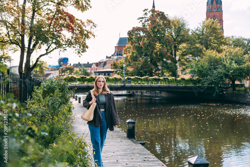 Young woman walking by river in Uppsala, Sweden
