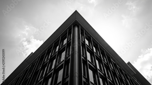 Minimalist monochrome design featuring a modern building corner converging towards a bright sky.