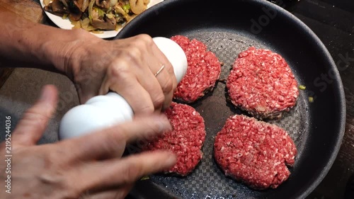 Stockholm, Sweden A cook in a residential kitchen fries homemade hamburger patties in a frying pan. 