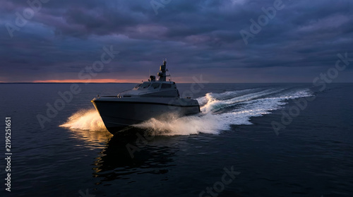 Military patrol boat speeding across dark water at dusk