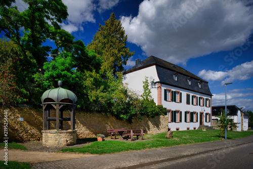 Obraz na płótnie Heritage-listed Haus Piedmont in Buervenich featuring a historic draw well, gree