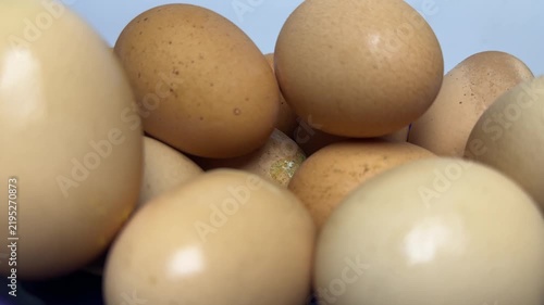 Brown and cream organic eggs stacked inside a glossy blue bowl with soft lighting and smooth textures. Perfect for healthy cooking or breakfast blog posts.