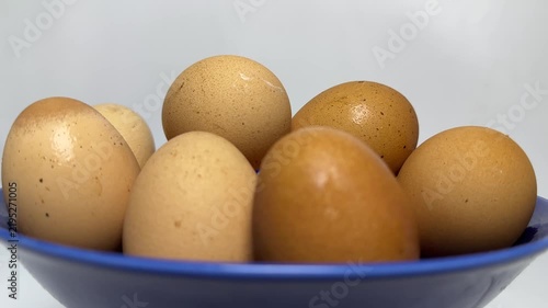 Brown and cream organic eggs stacked inside a glossy blue bowl with soft lighting and smooth textures. Perfect for healthy cooking or breakfast blog posts.