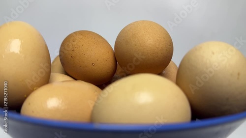Brown and cream organic eggs stacked inside a glossy blue bowl with soft lighting and smooth textures. Perfect for healthy cooking or breakfast blog posts.