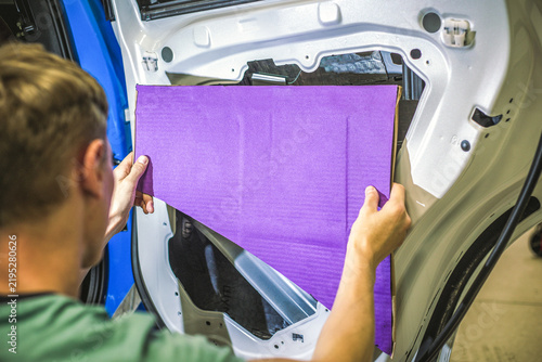 Konstfotografi Hands of a man install a purple soundproofing insulation sheet inside a disassembled car door close up
