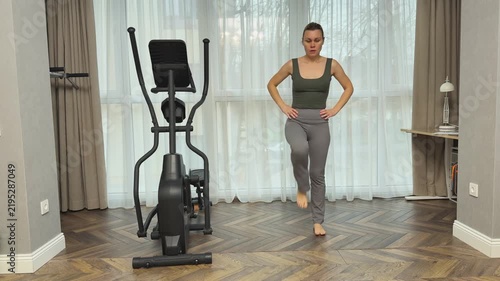  Woman performs marching steps lifting knees high while standing in living room. Simple home cardio routine for warmup and daily activity.