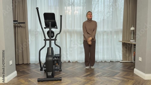Woman in sportswear lifts knees toward palms in controlled tempo. Home exercise for coordination and balance.