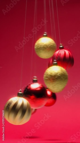 Pendulum of Hypnotic Christmas Balls Swinging in Front of Red Background