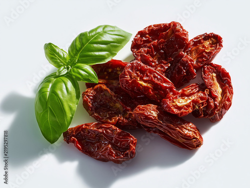Sun dried tomatoes and fresh basil leaves on white