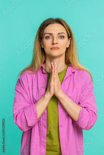 Konstfotografi Middle-aged woman folds hands in front of chest with pleading expression, showing hope, gratitude or asking for help