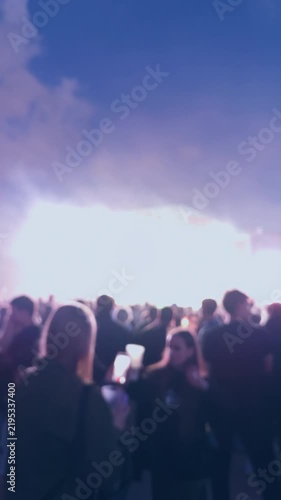 Blurred crowd watching bright stage lights at live music event with vibrant purple and pink atmosphere