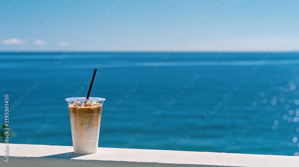 Fototapeta premium Refreshing Iced Coffee Drink with Creamy Layers on a Sunny Day with a Beautiful Ocean View